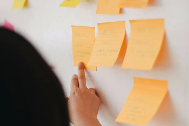 Hand an Post-its auf einem Whiteboard