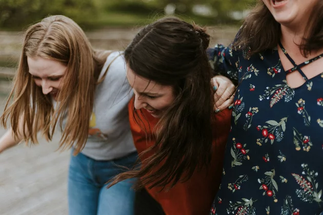 Drei junge Frauen umarmen sich und lachen